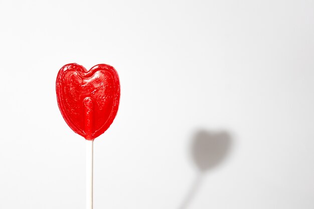 Closeup shot of a single heart-shaped lollipop on a white background