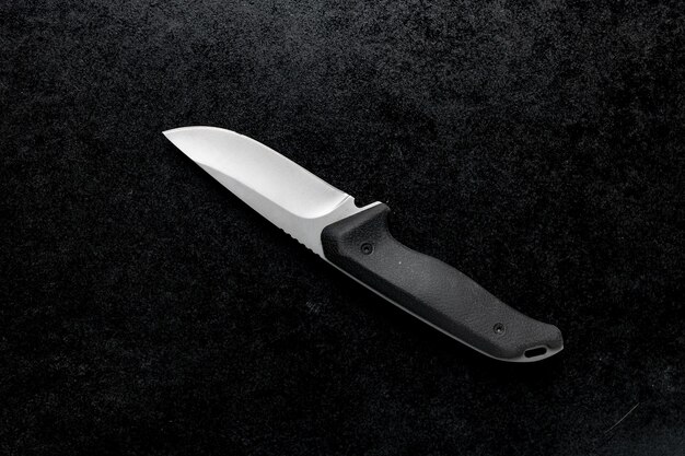 Closeup shot of a small combat knife with a black handle on the table