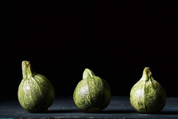 Closeup shot of small green pumpkins on black wall