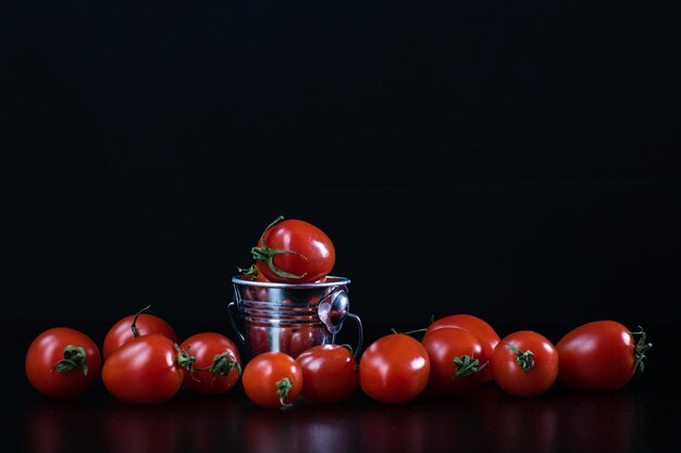 Closeup shot of a small metal bucket with cherry tomatoes isolated on a black background