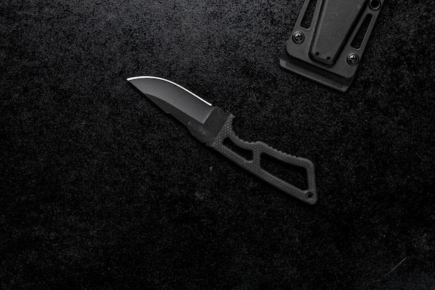 Closeup shot of a small sharp knife with a black handle on a black background