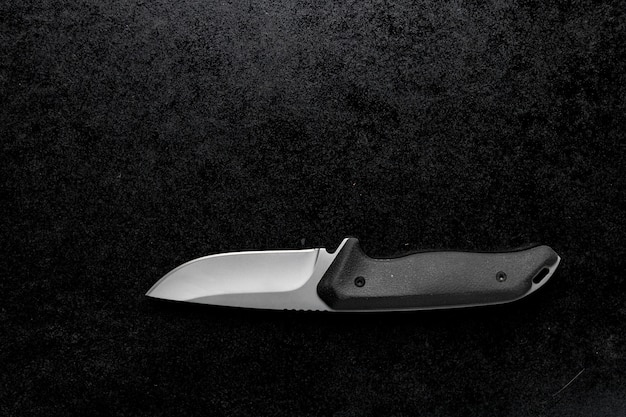 Closeup shot of a small sharp knife with a black handle on a black background