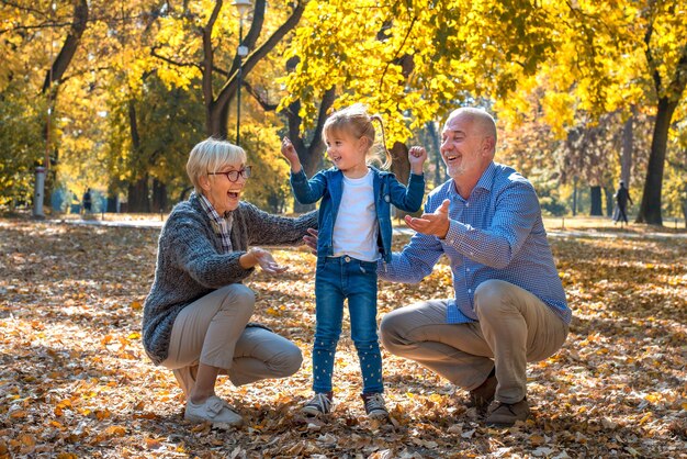 Closeup shot of smiling grandparents playing with their female grandchild in a park