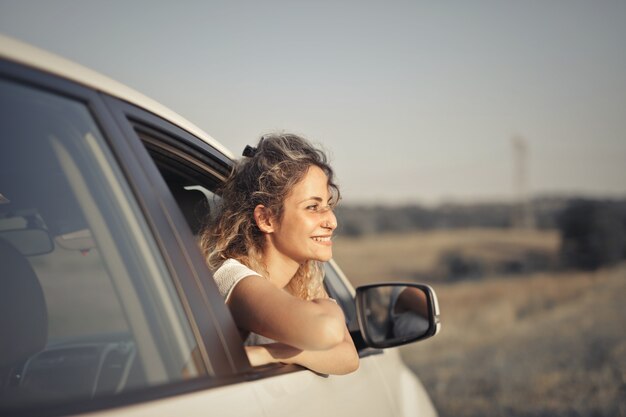 車から外を見ている笑顔の若い女性のクローズアップショット