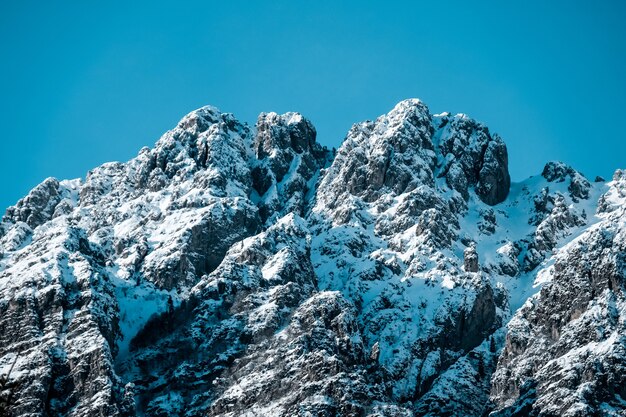 Снимок крупным планом заснеженных зубчатых горных вершин под чистым голубым небом