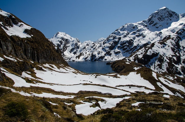 Closeup shot of snowy mountains and a lake from the Routeburn Track, New Zealand