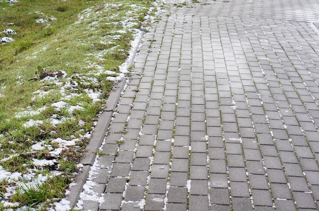 Foto gratuita primo piano di pavimentazione in pietra fatta di blocchi accanto all'erba in inverno