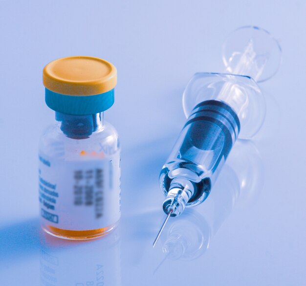 Closeup shot of a syringe and a vial on a glossy surface