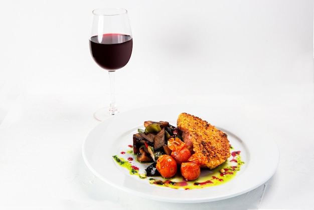 Closeup shot of a tasty looking dish near a wine glass isolated on white background