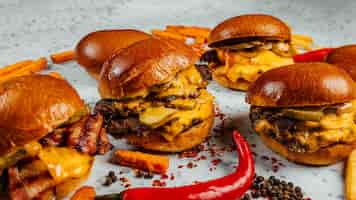 Free photo closeup shot of tasty smash burgers, french fries, and red spicy pepper on the white background