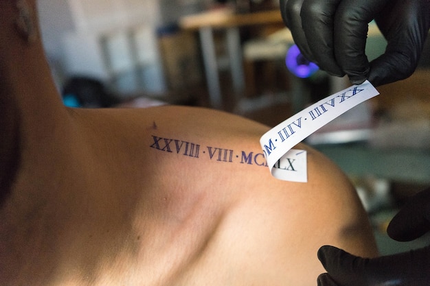 Free photo closeup shot of a tattoo artist placing a design on a client's shoulder