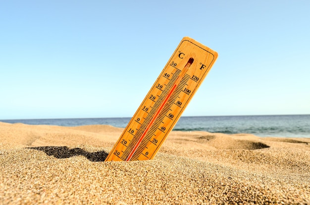 A closeup shot of a thermometer in the beach sand