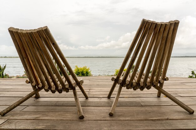 Closeup shot of two chairs in front of the ocean under a cloudy sky