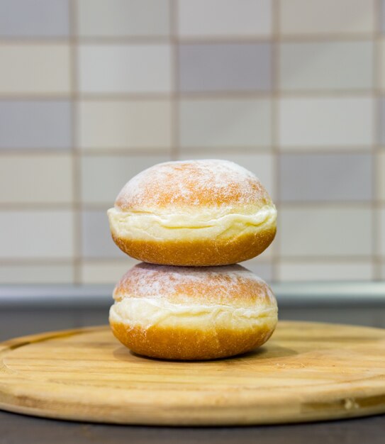 Closeup shot of two fresh sugar donuts on a wooden board