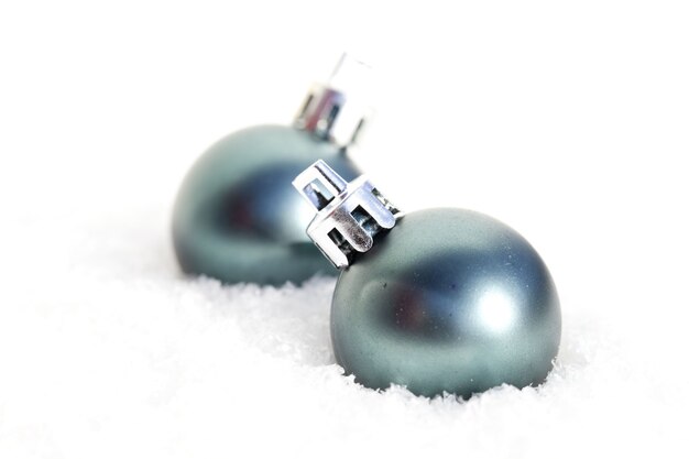 雪の中で2つの丸い青いクリスマスの飾りのクローズアップショット
