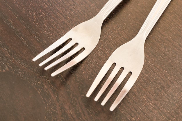 Closeup shot of two white plastic forks on a wooden surface