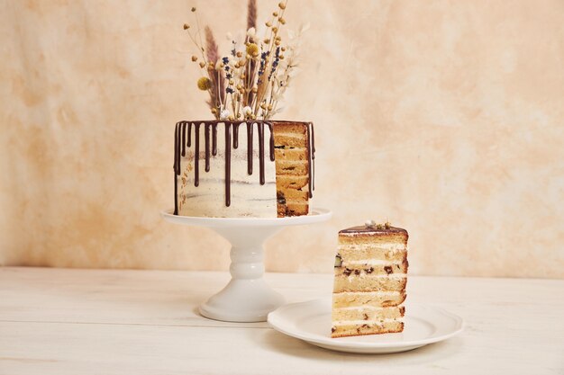 Снимок крупным планом ванильного торта с шоколадной каплей и цветами на вершине