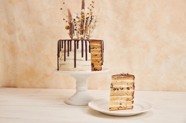 Closeup shot of a vanilla cake with chocolate drip and flowers on top