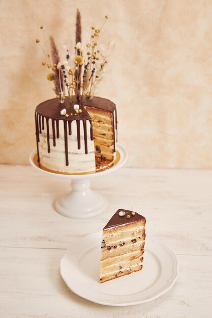 チョコレートのしずくと花が上にあるバニラケーキのクローズアップショット