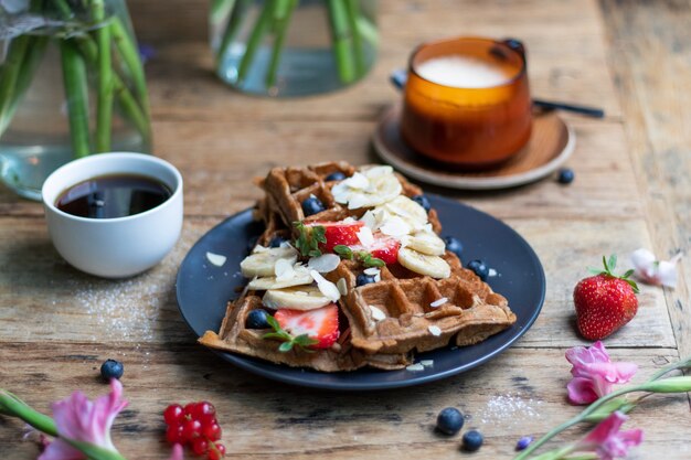 Closeup shot of waffles with fresh bananas and strawberries on it