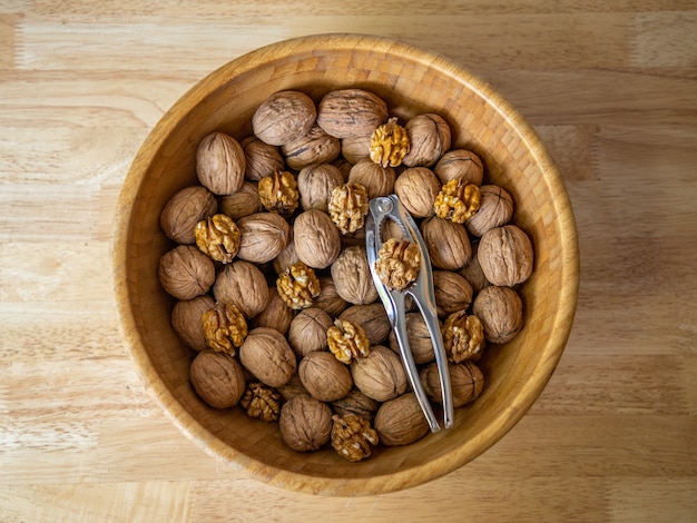 Free photo closeup shot of walnuts in a brown bowl on wooden background