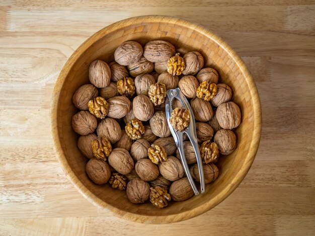 Closeup shot of walnuts in a brown bowl on wooden background