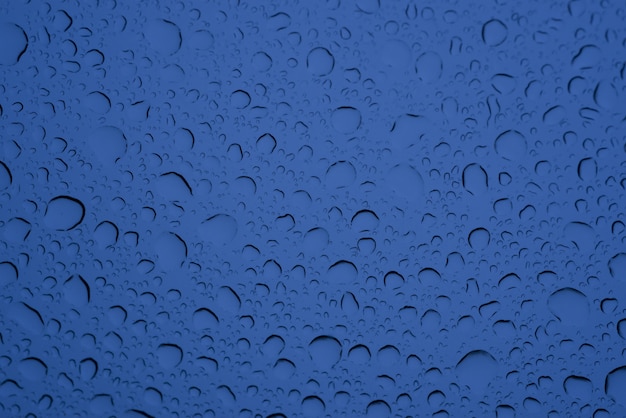 青いガラスの上の水の大小の滴のクローズアップショット-背景に最適