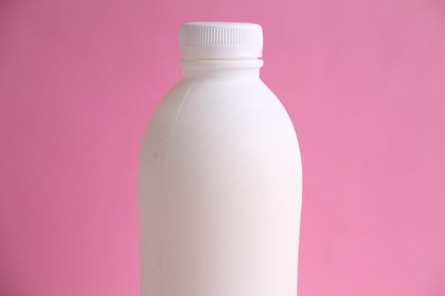 Primo piano di una bottiglia di plastica bianca su una superficie rosa
