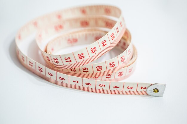 Closeup shot of a white and red tape measure on the table under the lights - designing concept