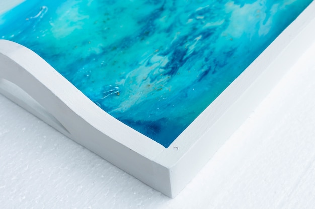 Free photo closeup shot of a white tray with epoxy resin art with blue inks