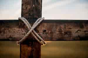 Free photo closeup shot of a wooden cross with a rope wrapped around and a blurred background