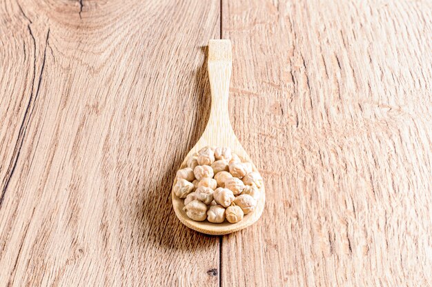 Closeup shot of a wooden spoon with raw chickpea