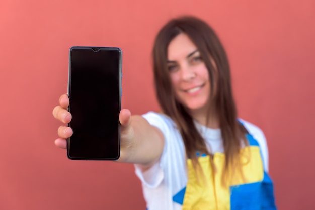 Closeup shot of a young female with her smartphone posing at camera