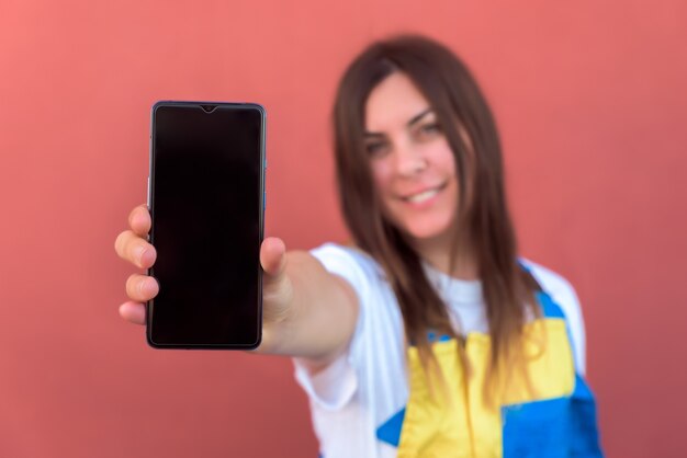 彼女のスマートフォンがカメラにポーズをとって若い女性のクローズアップショット