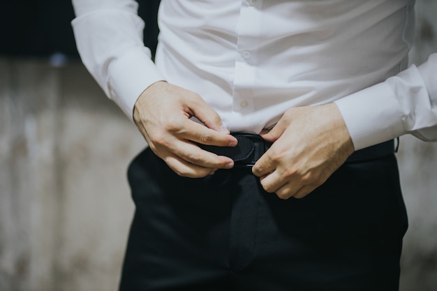 Closeup shot of a young and handsome groom getting dressed.