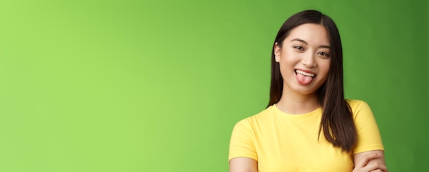 Free photo closeup silly cute flirty asian girl fool around childish playfully communicate boyfriend show tongue smiling broadly cross hands chest casually enjoy summer holidays green background