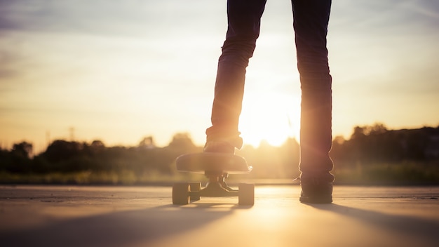 Foto gratuita primo piano di un guidatore di skateboard circondato da alberi sotto la luce del sole durante il tramonto