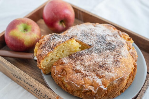 Closeup of a sliced apple pie with sugar powder on a plate on the table