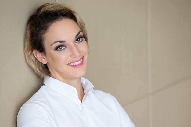 Closeup of Smiling Adult Woman Leaning on Wall