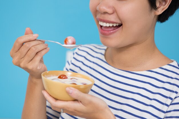 토마토 Raita를 먹고 웃는 아시아 여자의 근접 촬영