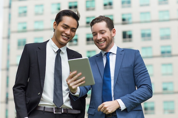 Макрофотография улыбающихся сотрудников с использованием планшета за пределами