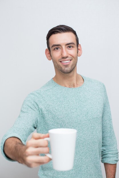 茶のマグカップを提供する笑顔のハンサムな男の拡大