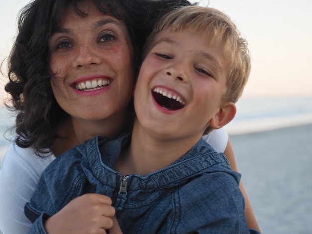 Primo piano di sorridente madre e figlio in spiaggia sotto la luce del sole