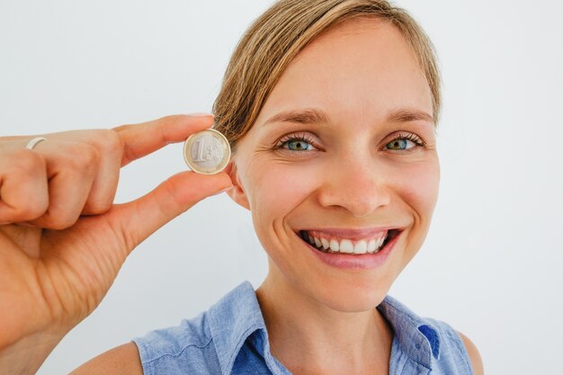 1つのユーロのコインを持っている笑顔の女性の拡大