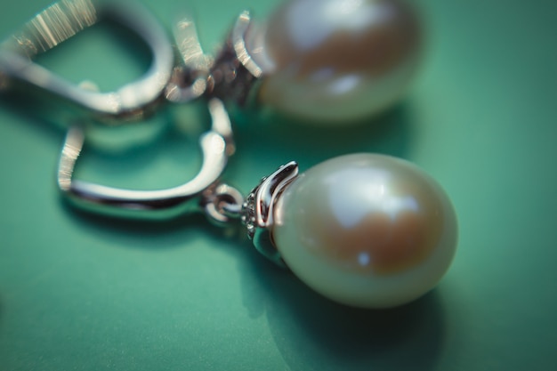 ミント紙に横たわる輝く真珠のイヤリングの拡大写真