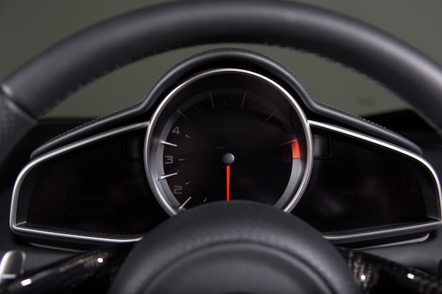 Closeup of a speedometer and a steering wheel of a modern car under the lights