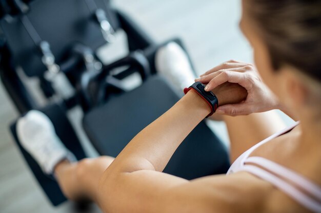 Closeup of sportswoman using fitness tracker while working out in a gym