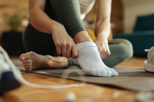 Closeup of sportswoman wearing white socks while preparing for workout at home