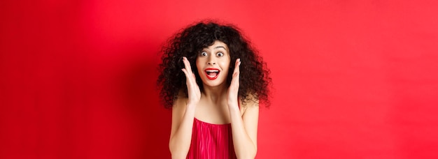 Closeup of surprised beautiful woman screaming of amazement and looking at promo offer standing in r