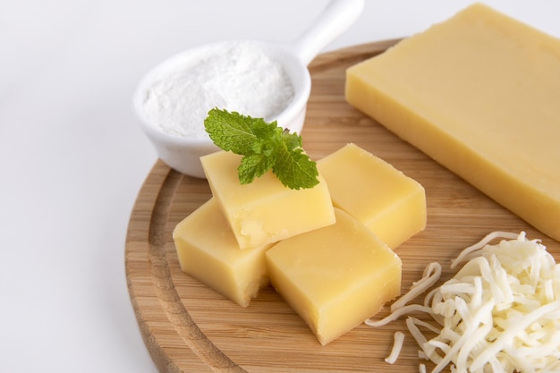 Closeup of Swiss Cheese cubes and slices on a board isolated on a gray background